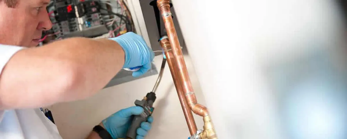 Water heater repair technician testing copper pipe connections and controls in Concord, MA